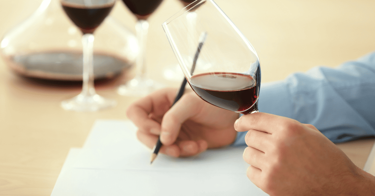 Pessoa escrevendo notas de degustação de um vinho.