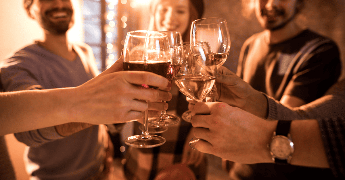 Pessoas unindo taças de vinho para fazer um brinde.